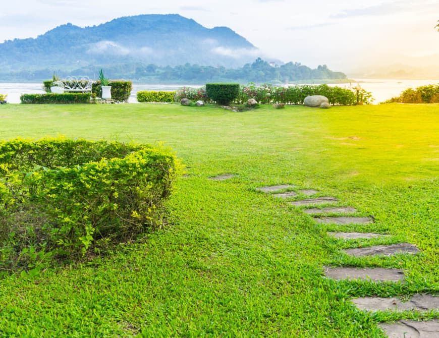 A Stone Path Leading Through a Lush Green Field With Mountains in the Background — Totally Skip Bins In Flagstone, QLD