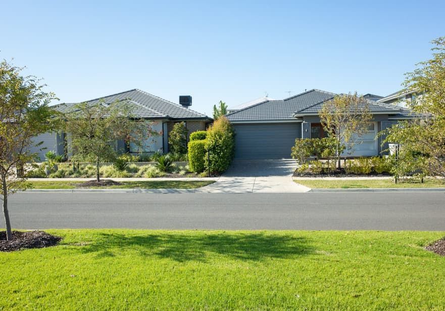 A Row of Houses Sitting Next to Each Other on a Lush Green Lawn — Totally Skip Bins in Cedar Vale, QLD
