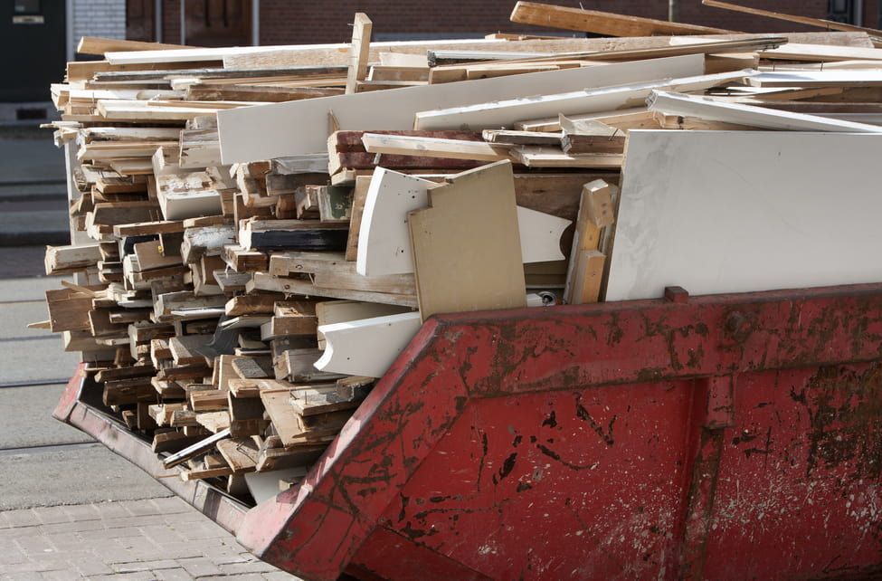 A Red Dumpster Filled With a Pile of Wood — Totally Skip Bins in Tamborine, QLD