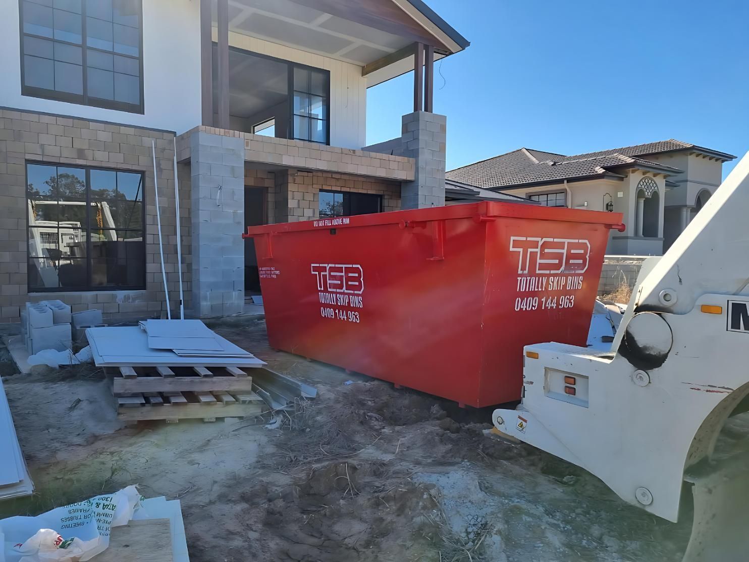 Red Skip Bin Hire Positioned At A Home Renovation Site With A Forklift