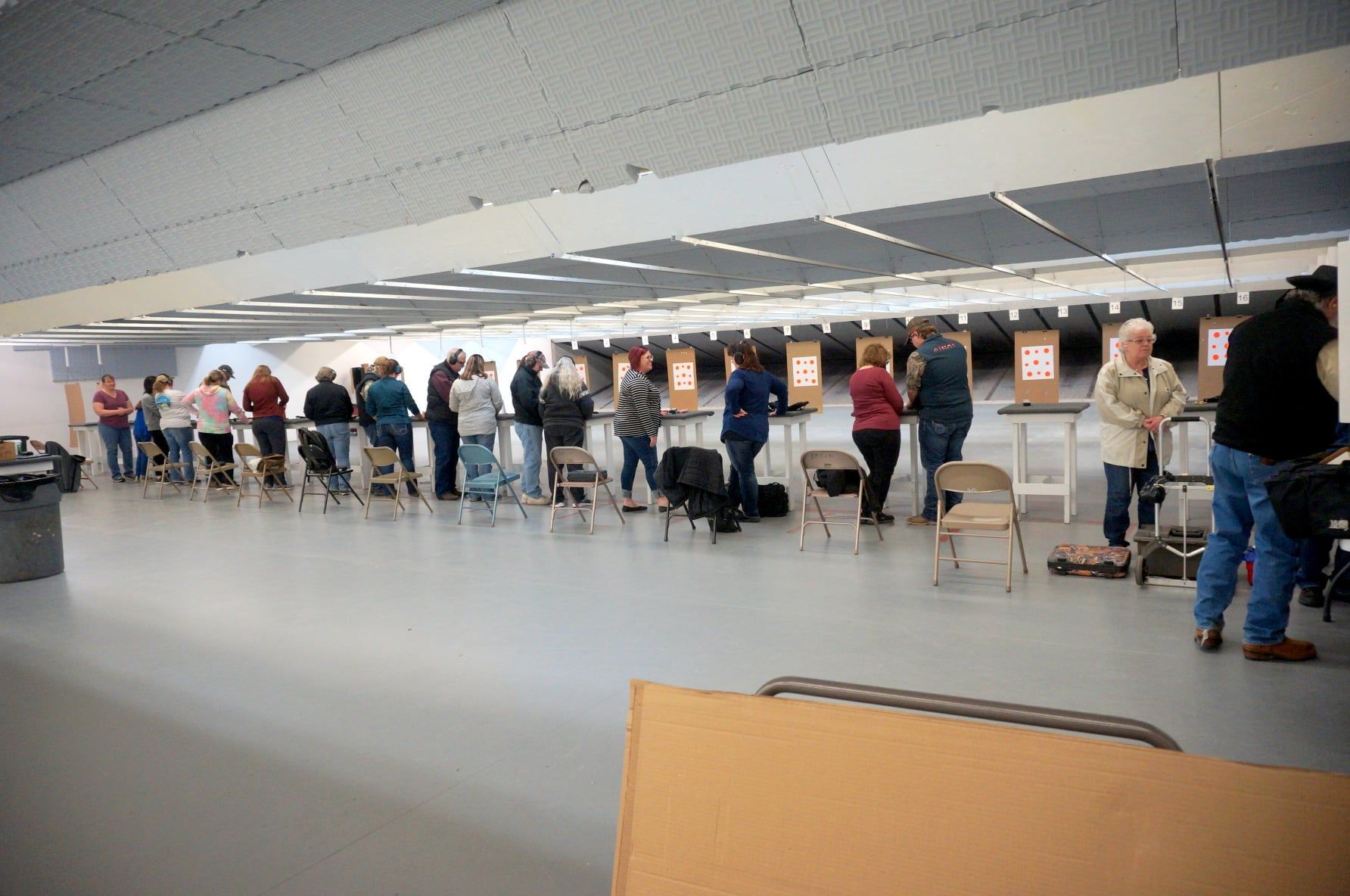A group of people are standing in a room with tables and chairs.