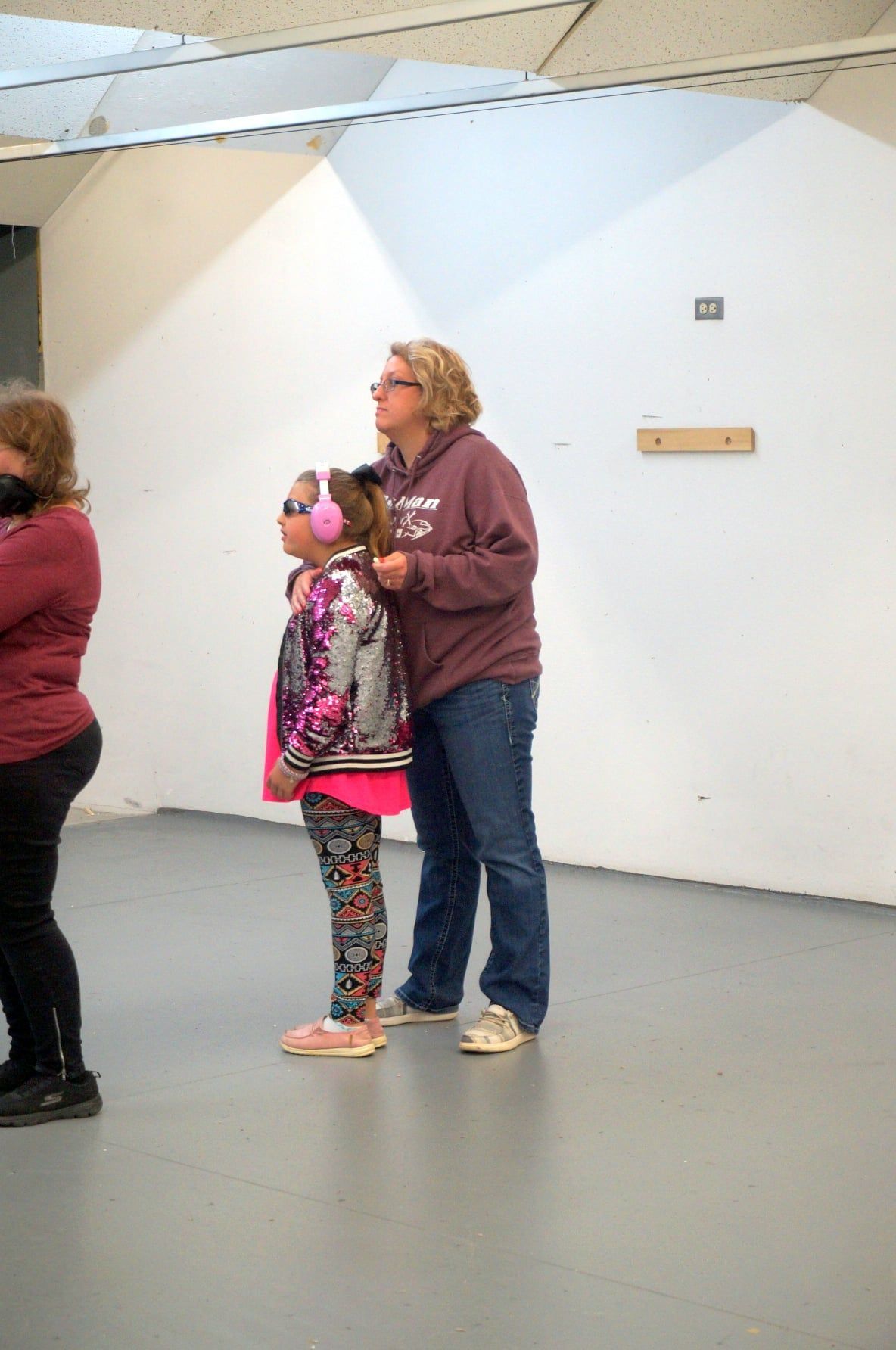A woman is standing next to a little girl in a room.