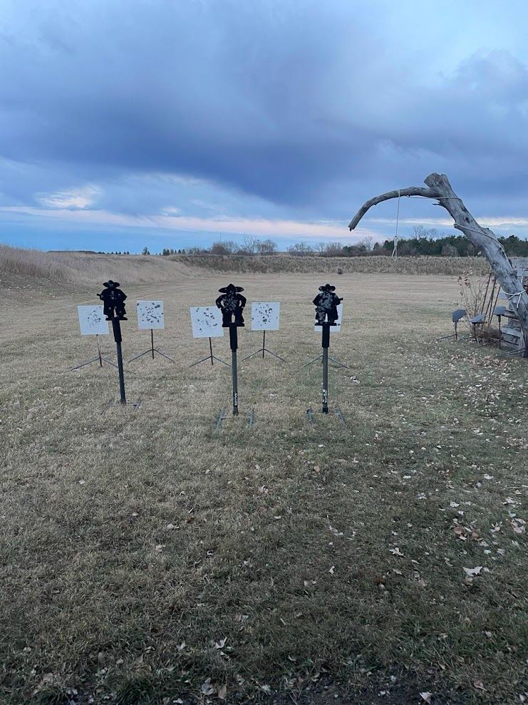 A row of targets in a field with a cloudy sky in the background.