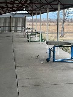 A row of picnic tables under a canopy in a park.