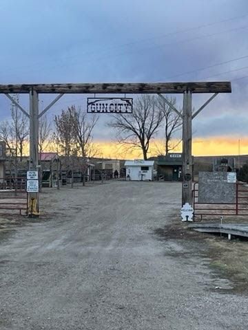 A dirt road with a wooden archway and a sign that says ' ranch ' on it.
