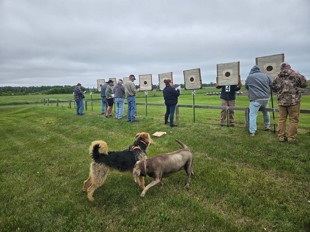 A group of people and dogs are standing in a field.