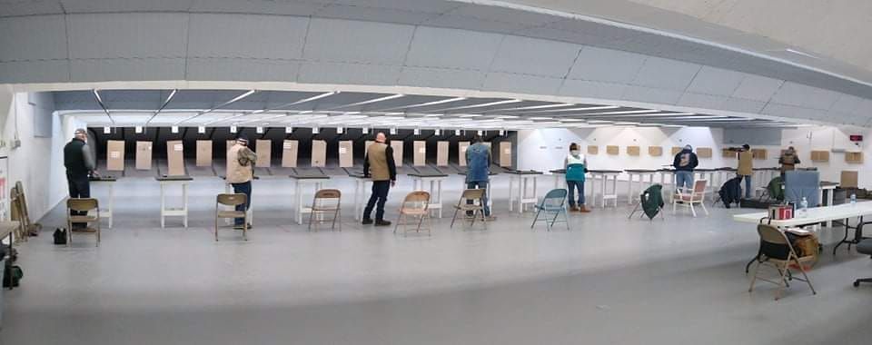 People standing in a shooting range, ready to shoot at targets.