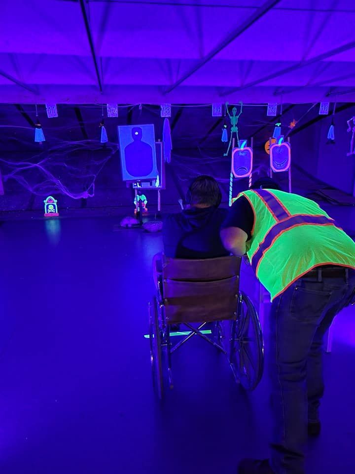 A man in a glow in the dark vest is pushing a man in a wheelchair.