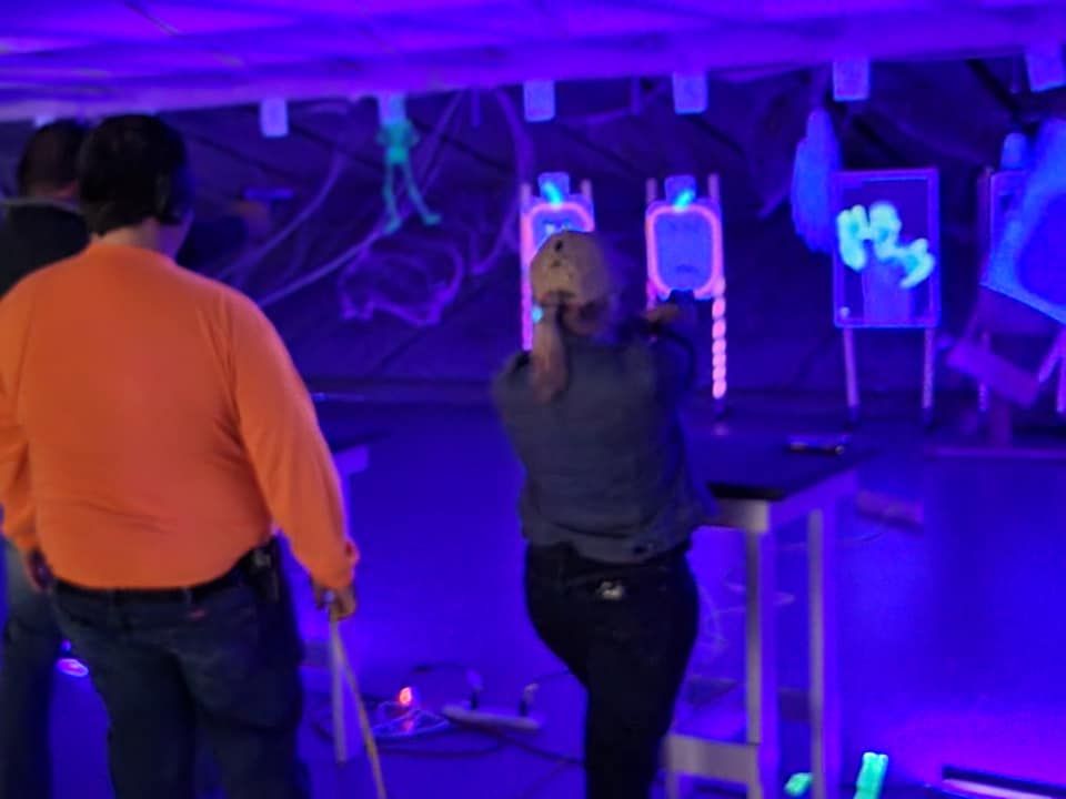 A woman is standing in front of a glow in the dark target in a dark room.