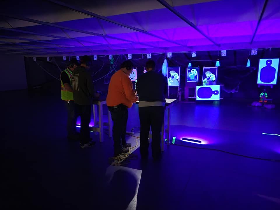 A group of people are standing in a dark room with purple lights.