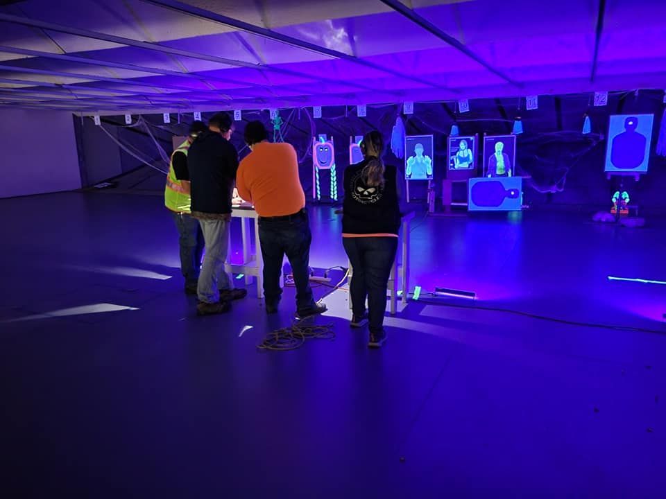 A group of people are standing in a room with purple lights.