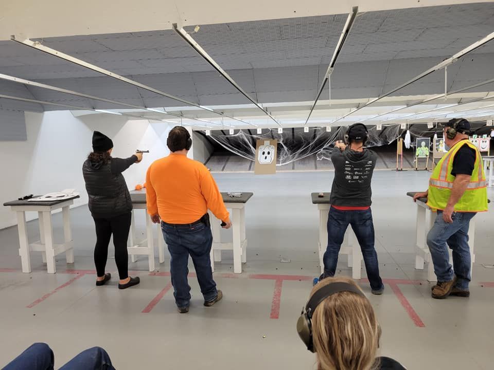 People shooting firearms at targets in an indoor gun range.