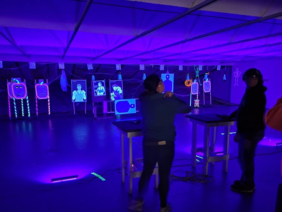 Two people are standing in a dark room with glow in the dark targets.