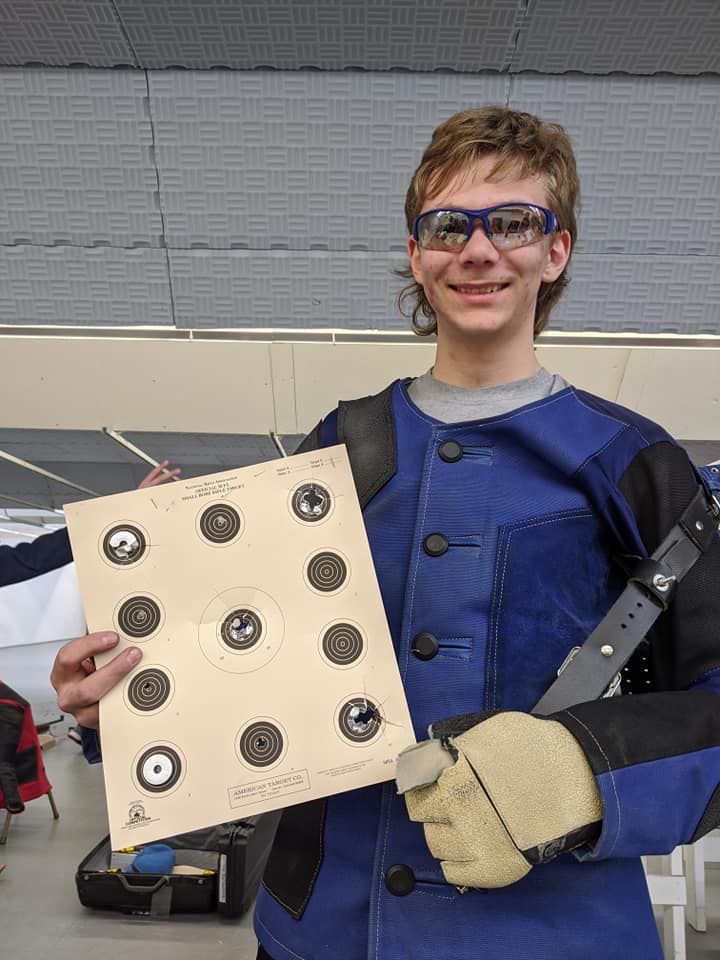 A young man in a blue jacket is holding a target.