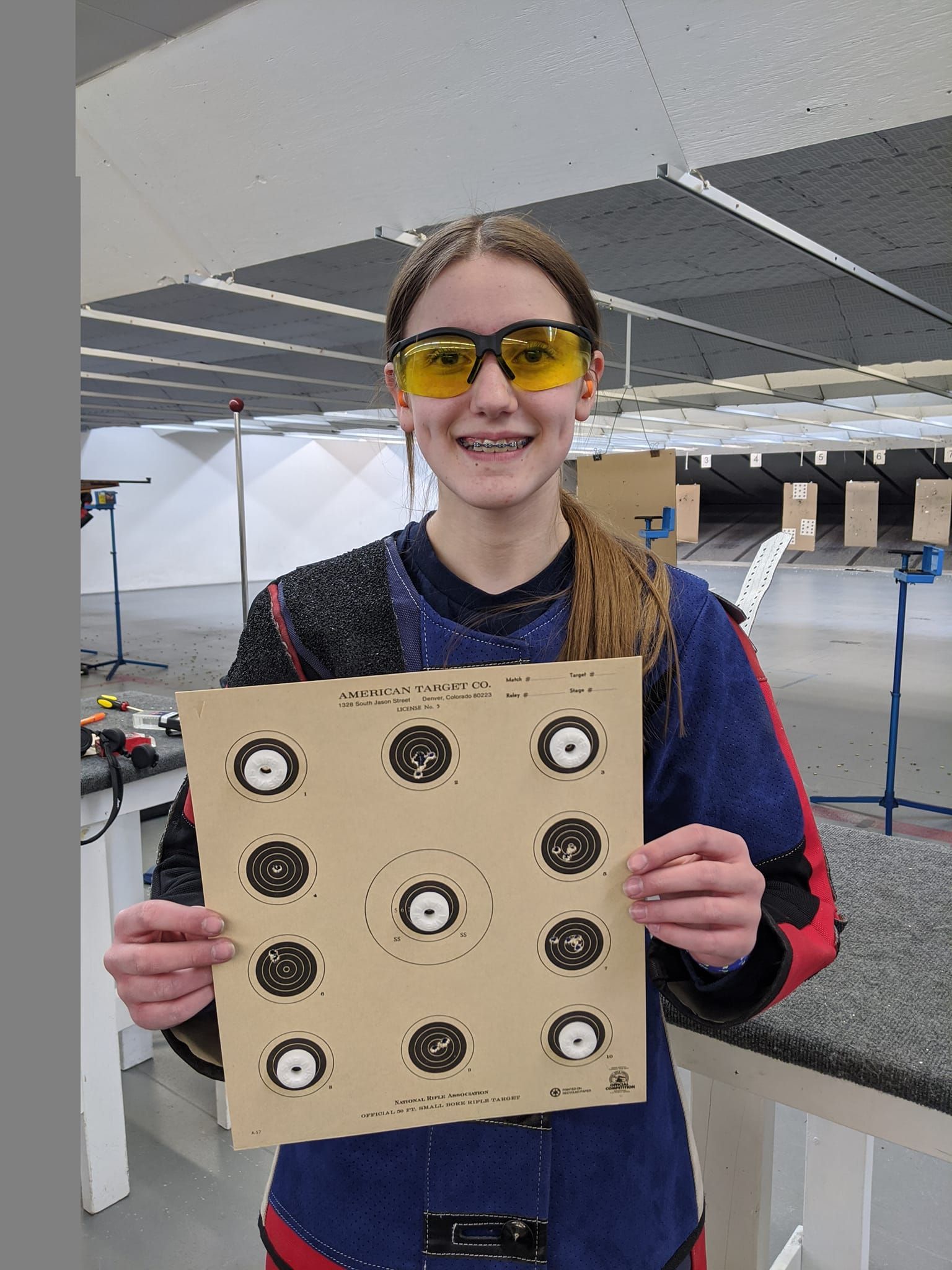 A woman wearing yellow glasses is holding a target in her hands.