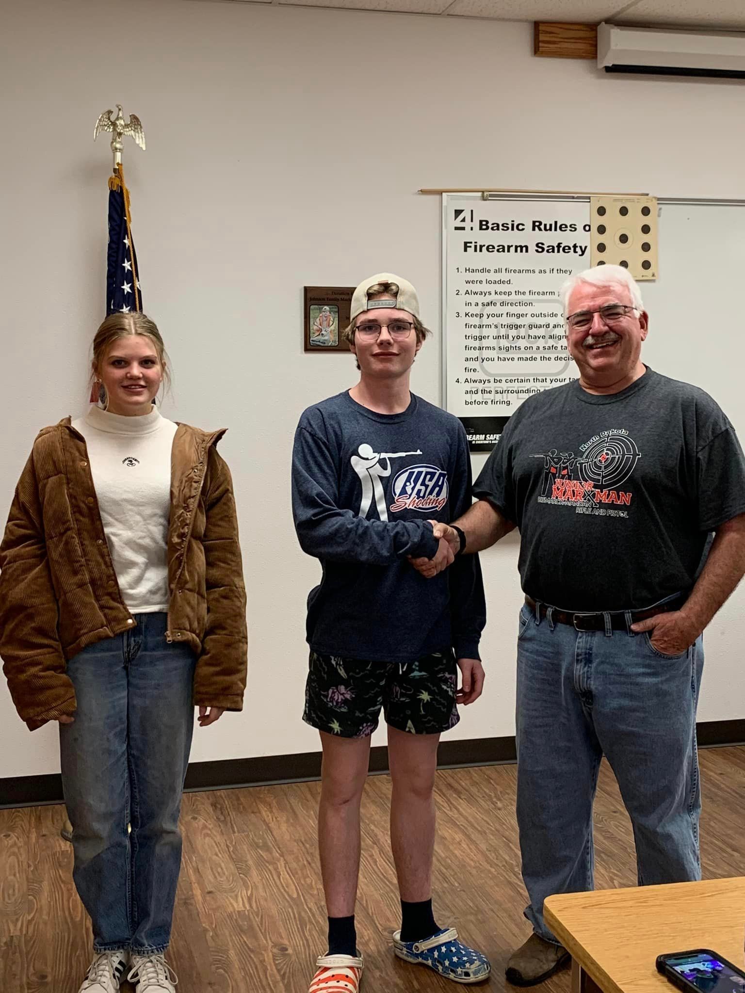 A man and two women are shaking hands in a room.