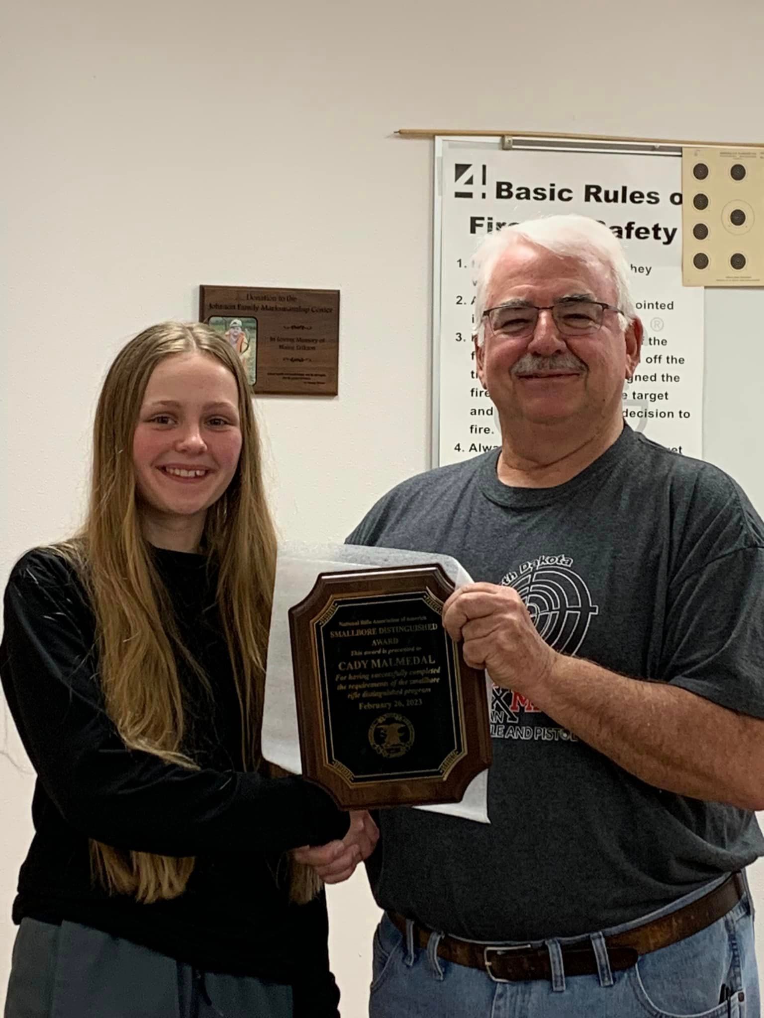 A man and a woman are shaking hands while holding a plaque.