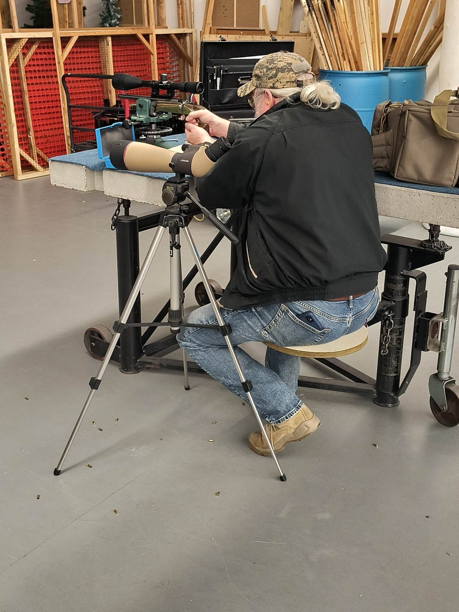 A man is kneeling down while looking through a telescope