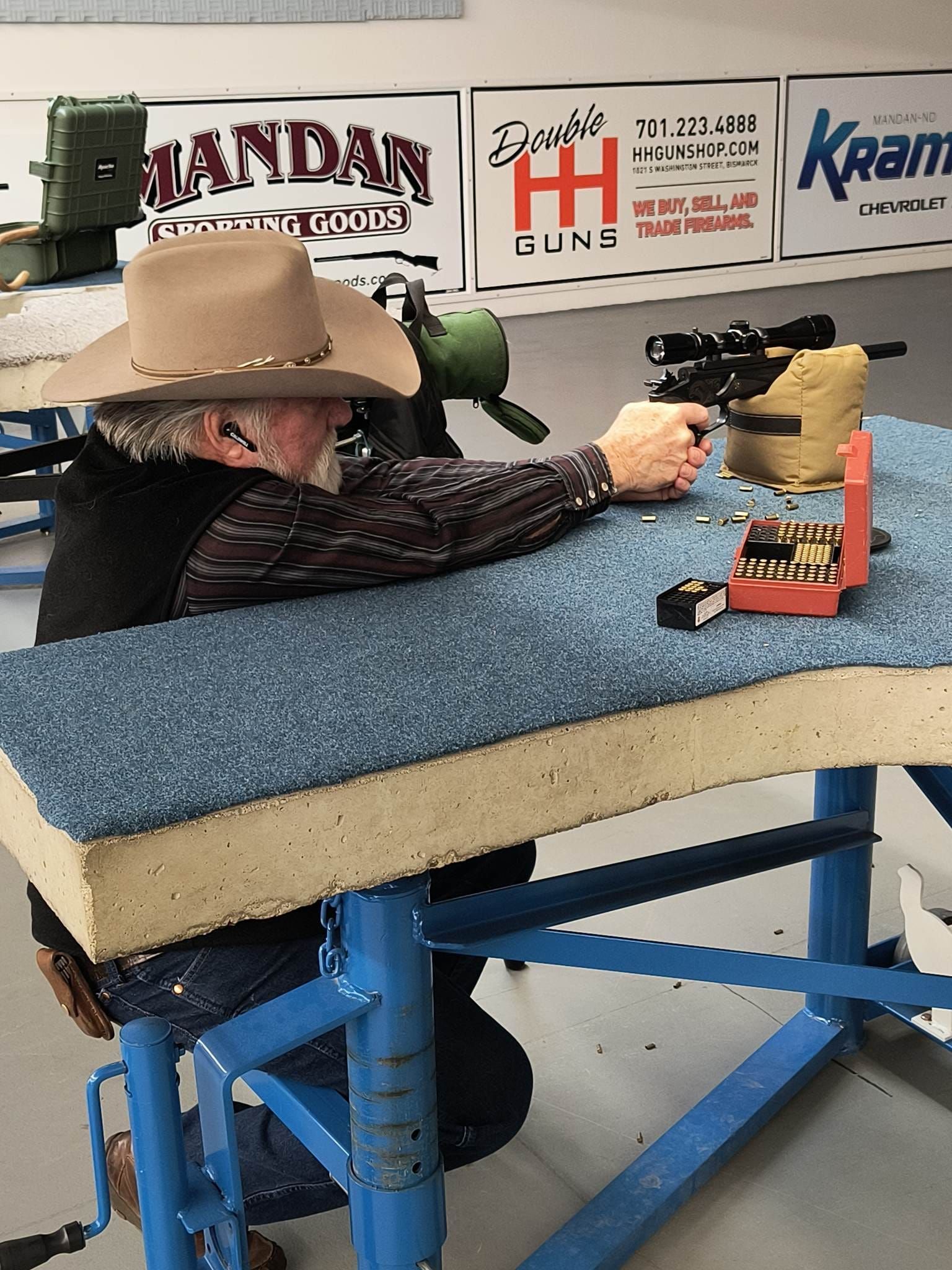 Man in cowboy hat shooting rifle at a shooting range.