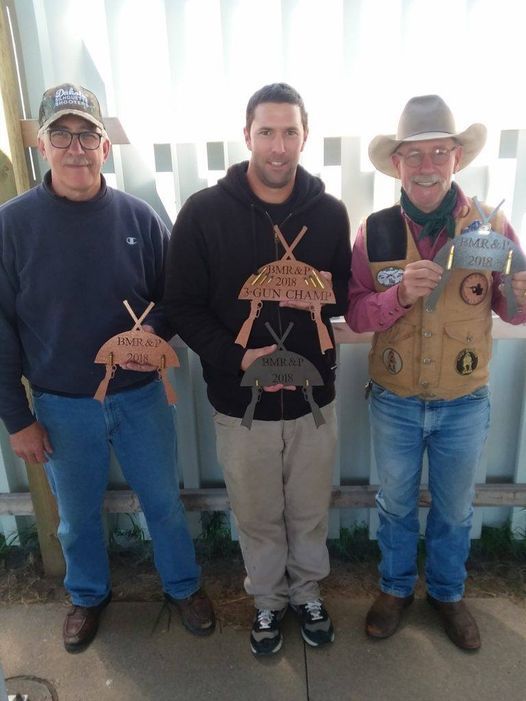 Three men are standing next to each other holding trophies