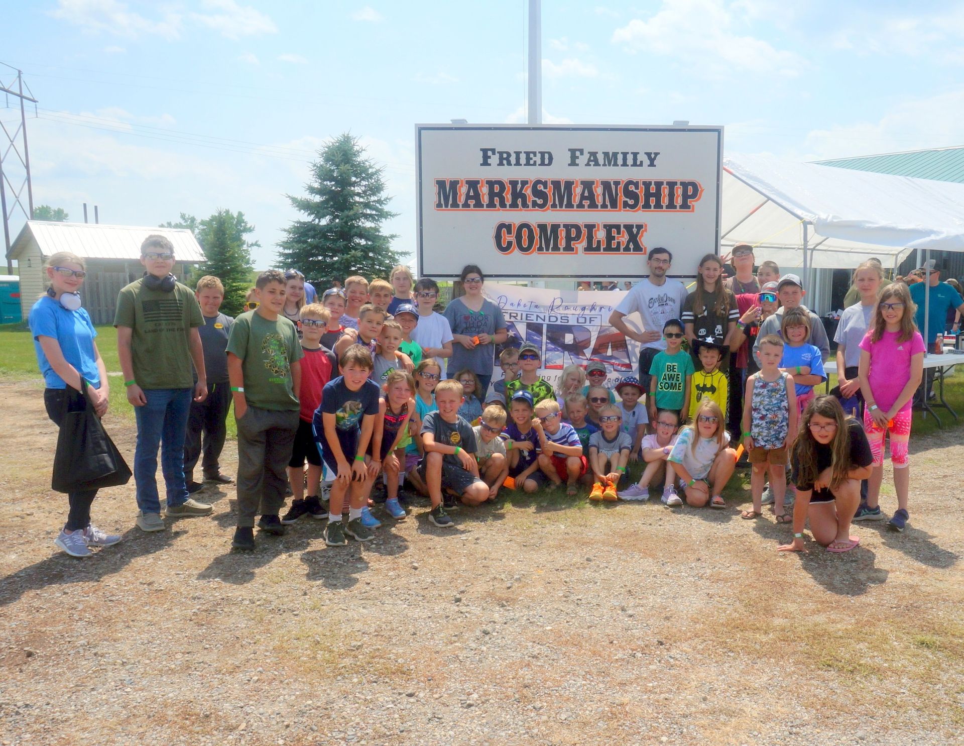 A group of people standing in front of a sign that says fritz family marksmanship complex