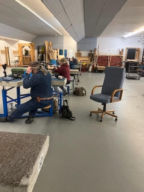 A group of people are working in a room with a chair in the middle