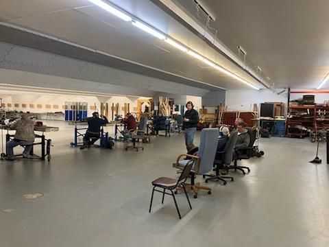 A group of people are sitting at tables and chairs in a large room.