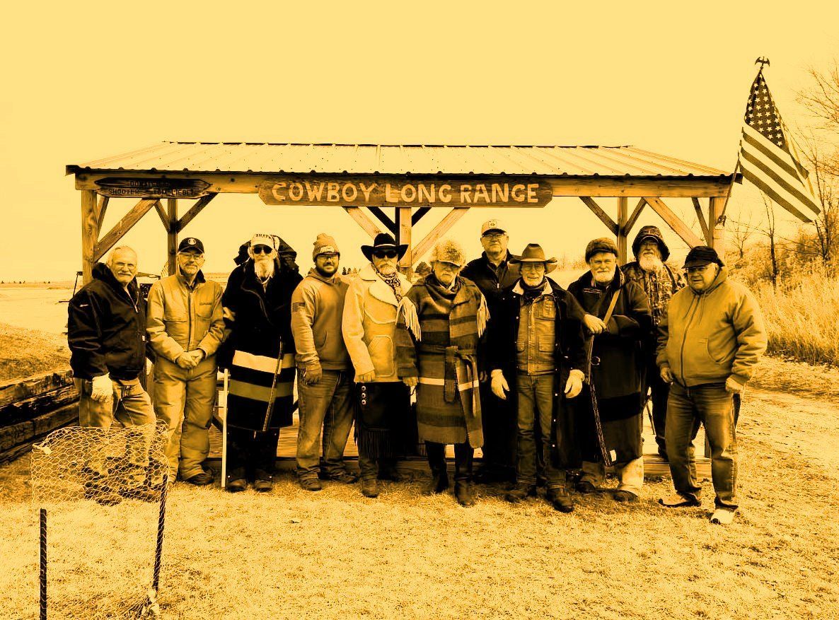 A group of people standing under a cowboy long range sign