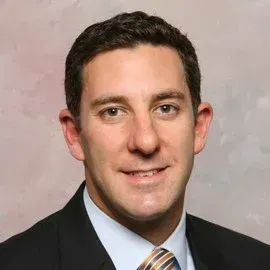 A man in a suit and tie is smiling for the camera.