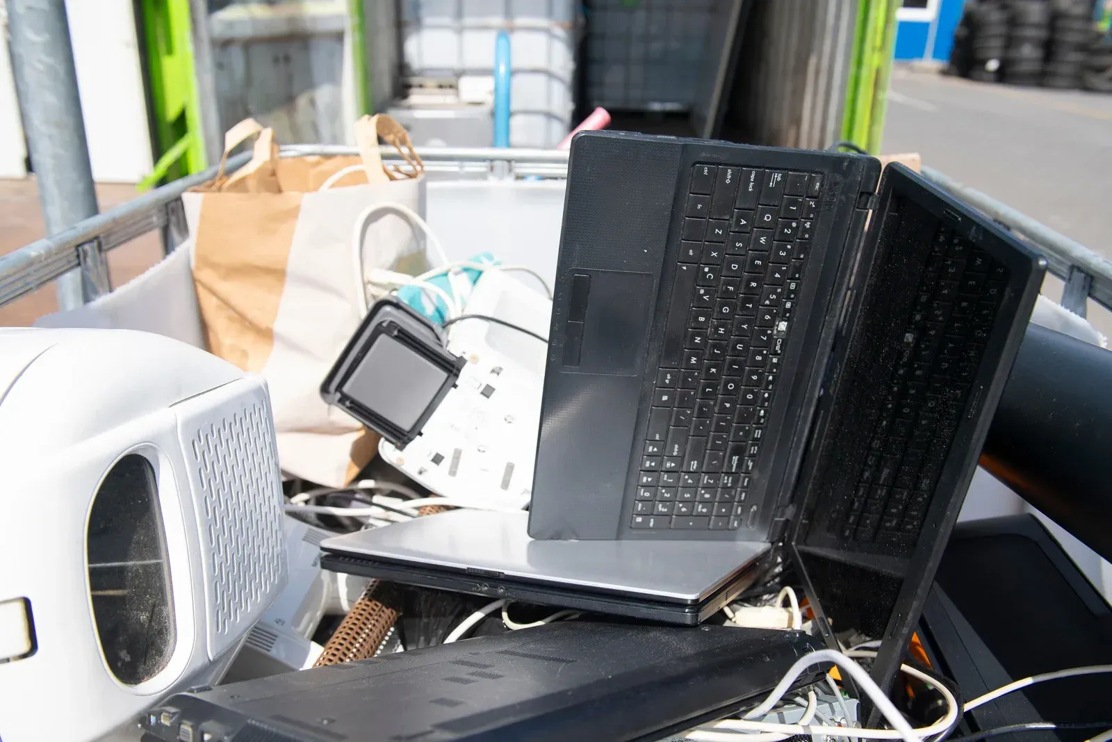 Tangled electronics, including a black laptop and cables, piled on a bus seat by the window