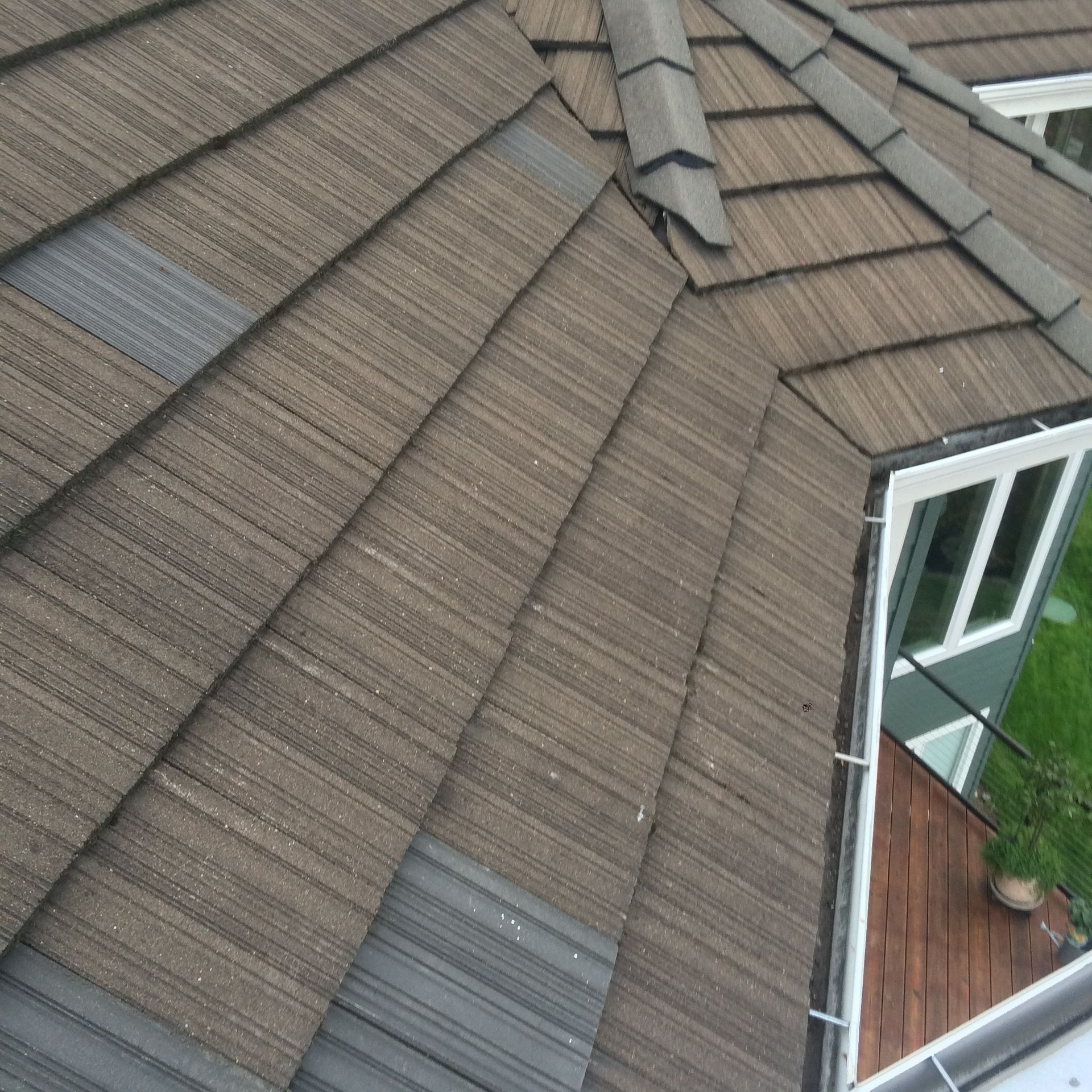 Power washing a red tile roof; person holding nozzle sprays water.