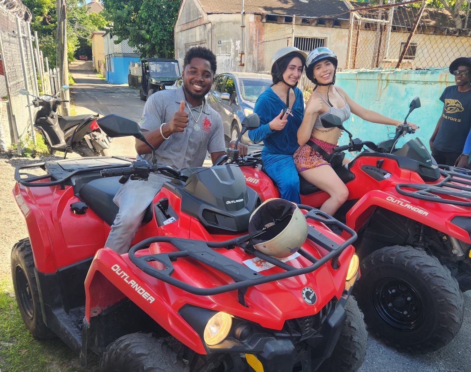 A man and two women are sitting on red outlander atvs