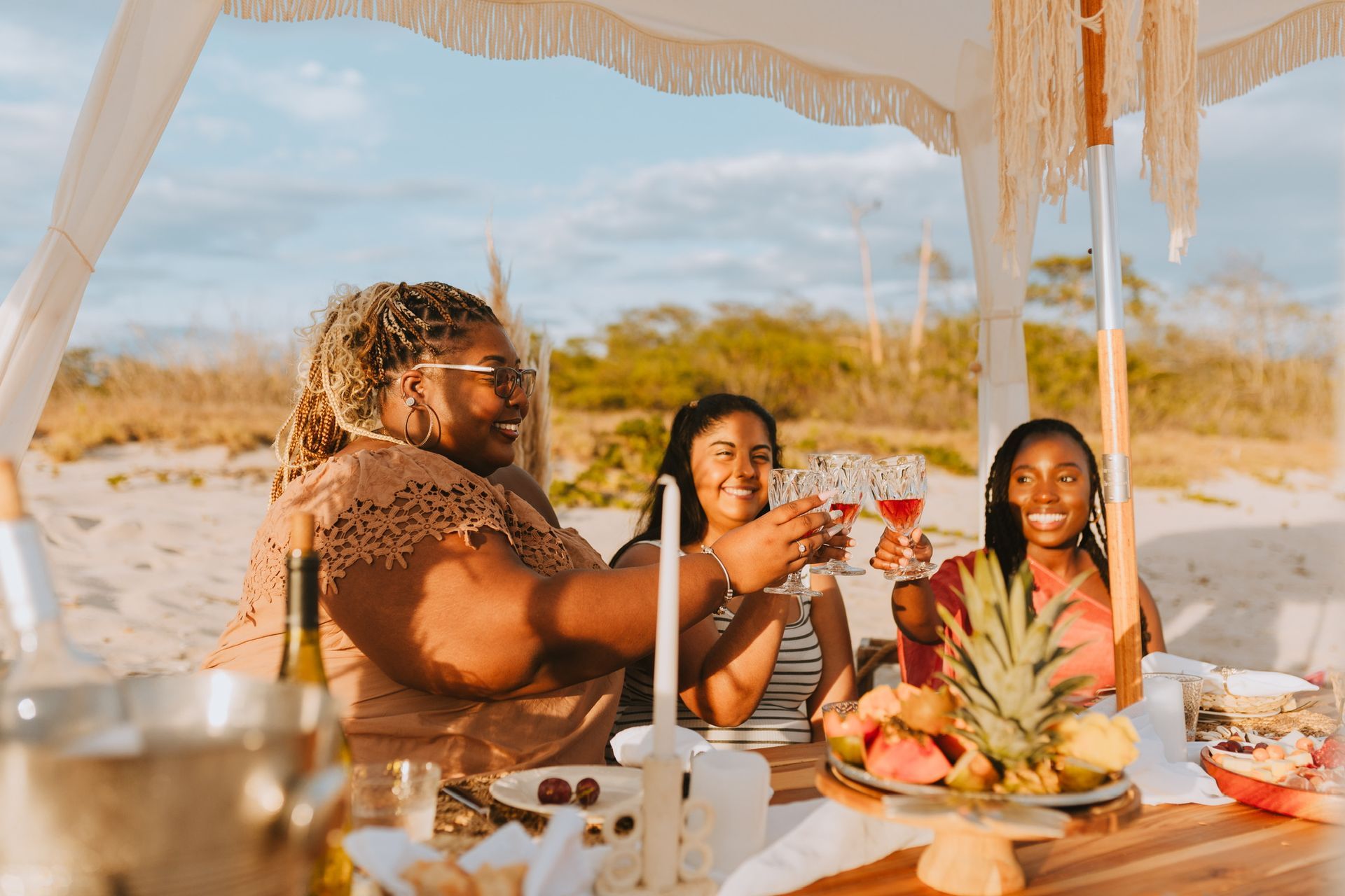 A group of women are sitting at a table on the beach.