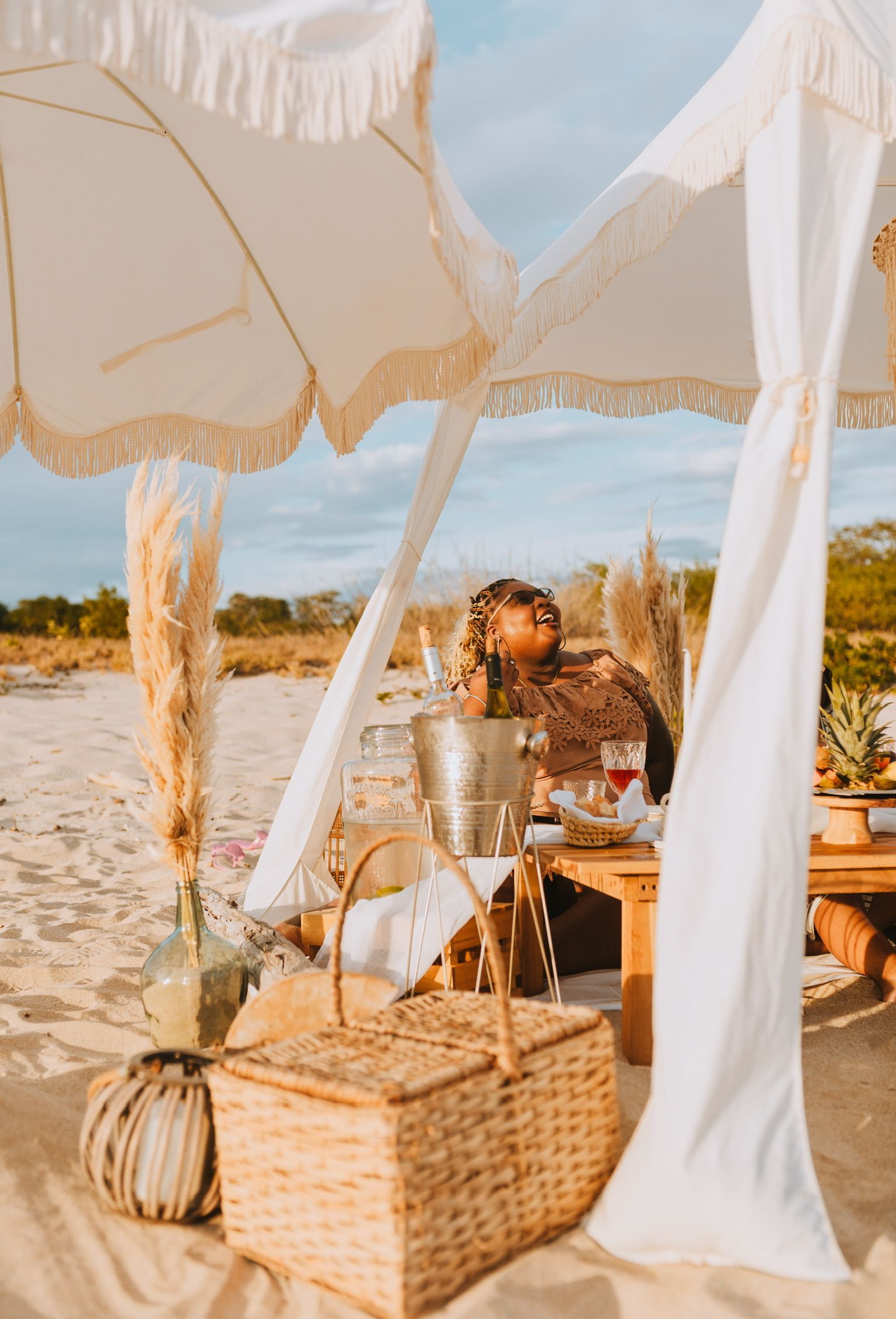 A woman is sitting under an umbrella on the beach.