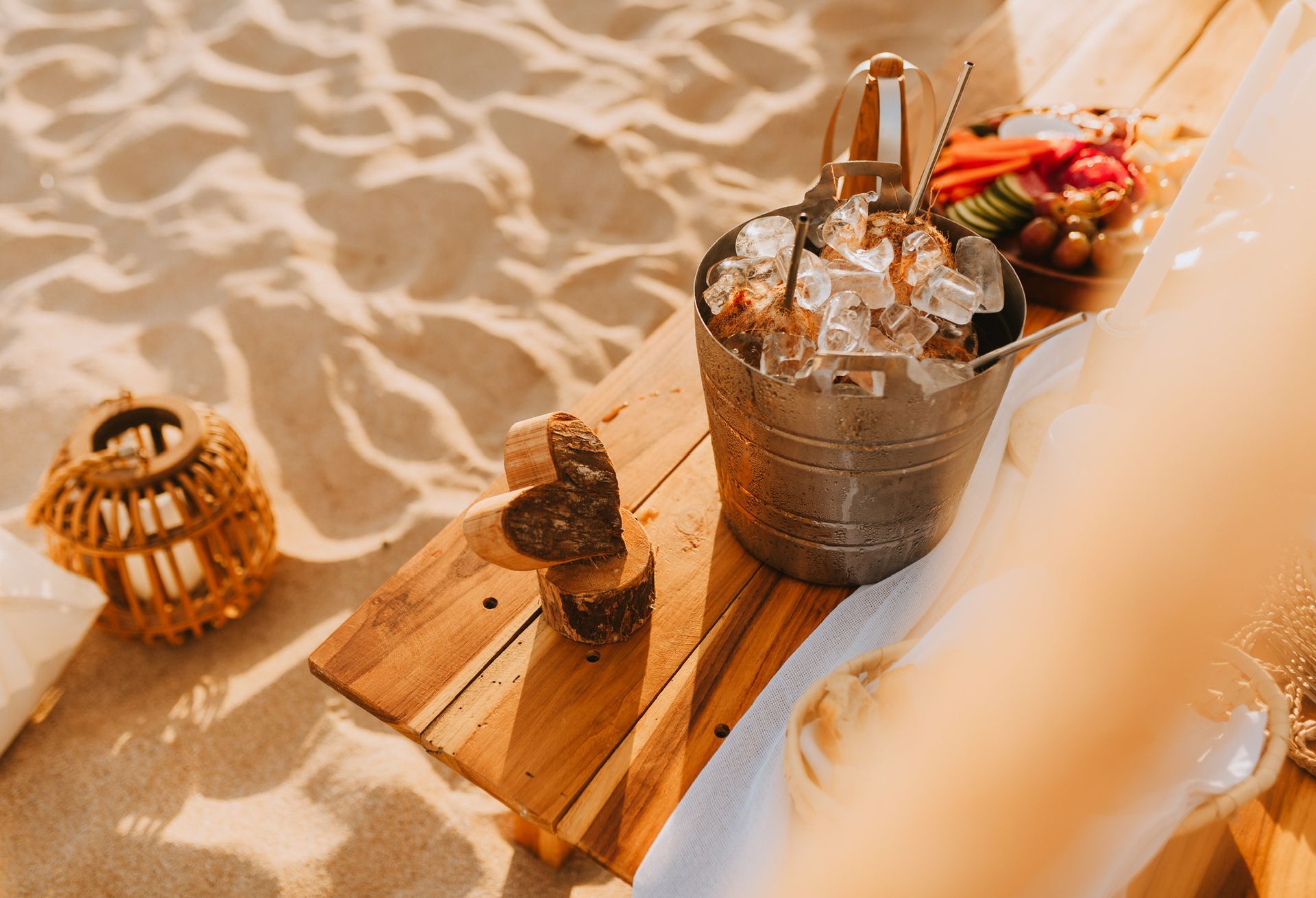 A bucket of ice is sitting on a wooden table on the beach.