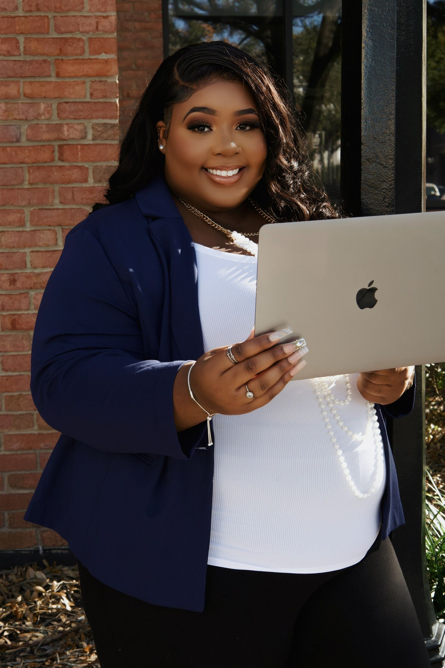 A woman in a blue jacket is holding an apple laptop.
