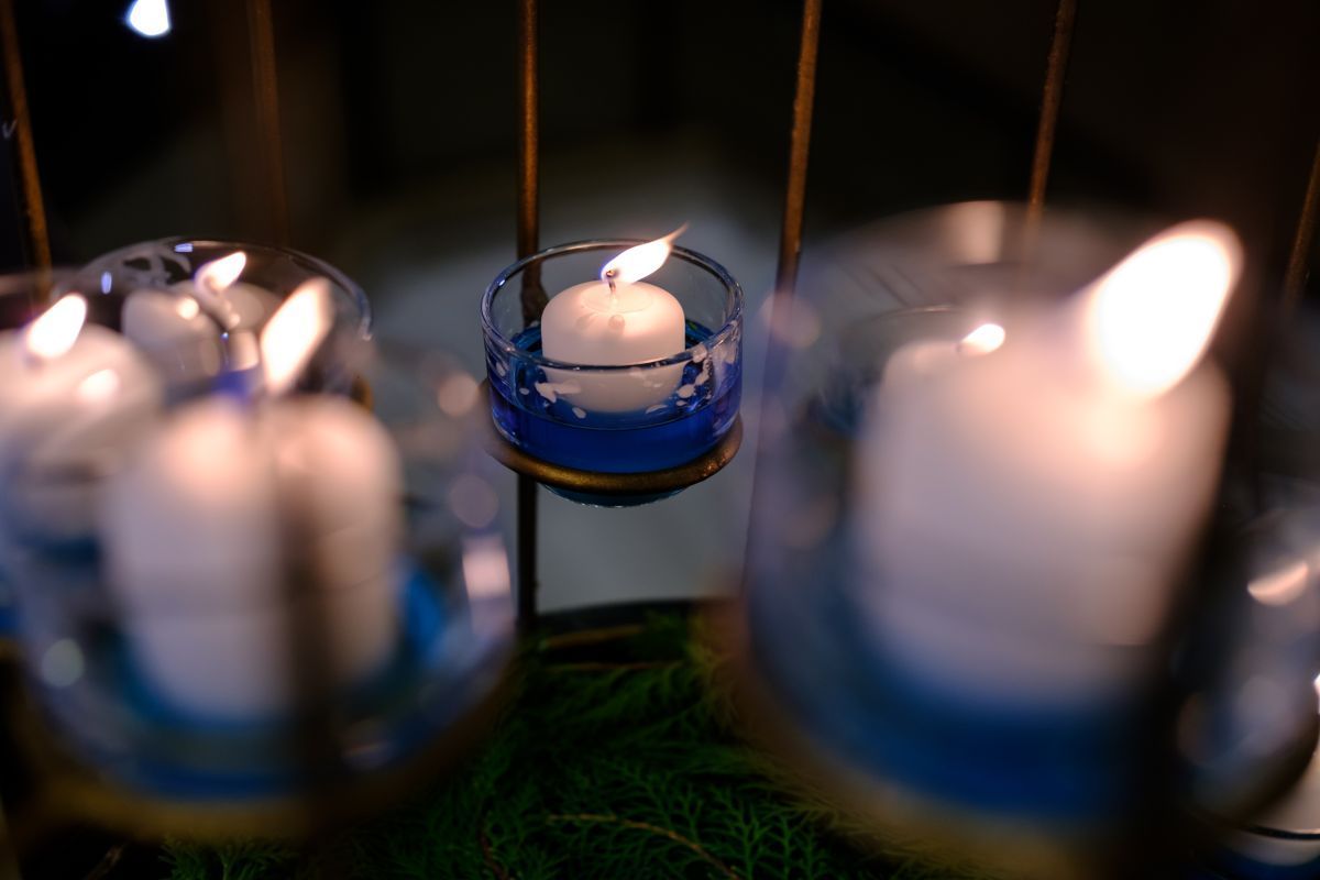 Blue glass candle holders with lit white candles glowing in the dark