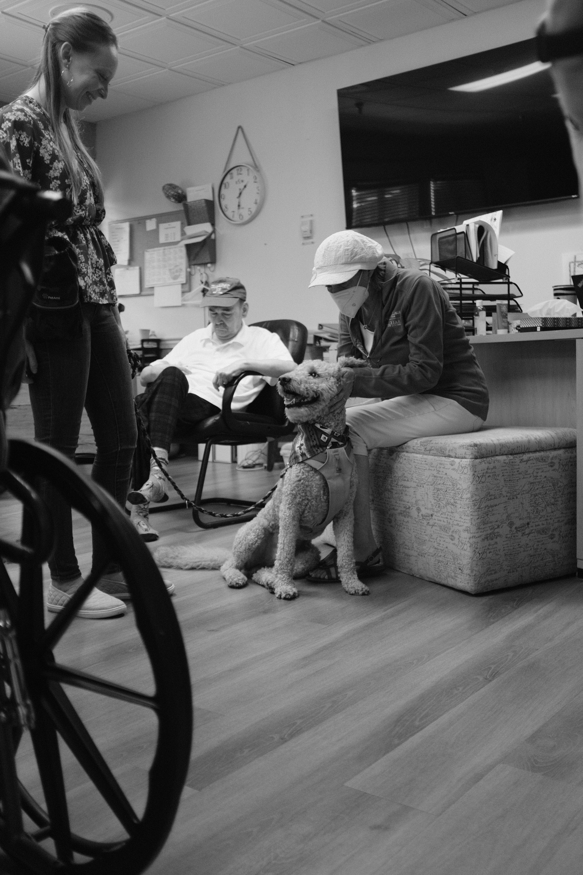 A black and white portrait of a young woman handles her therapy dog at an assisted living facility.
