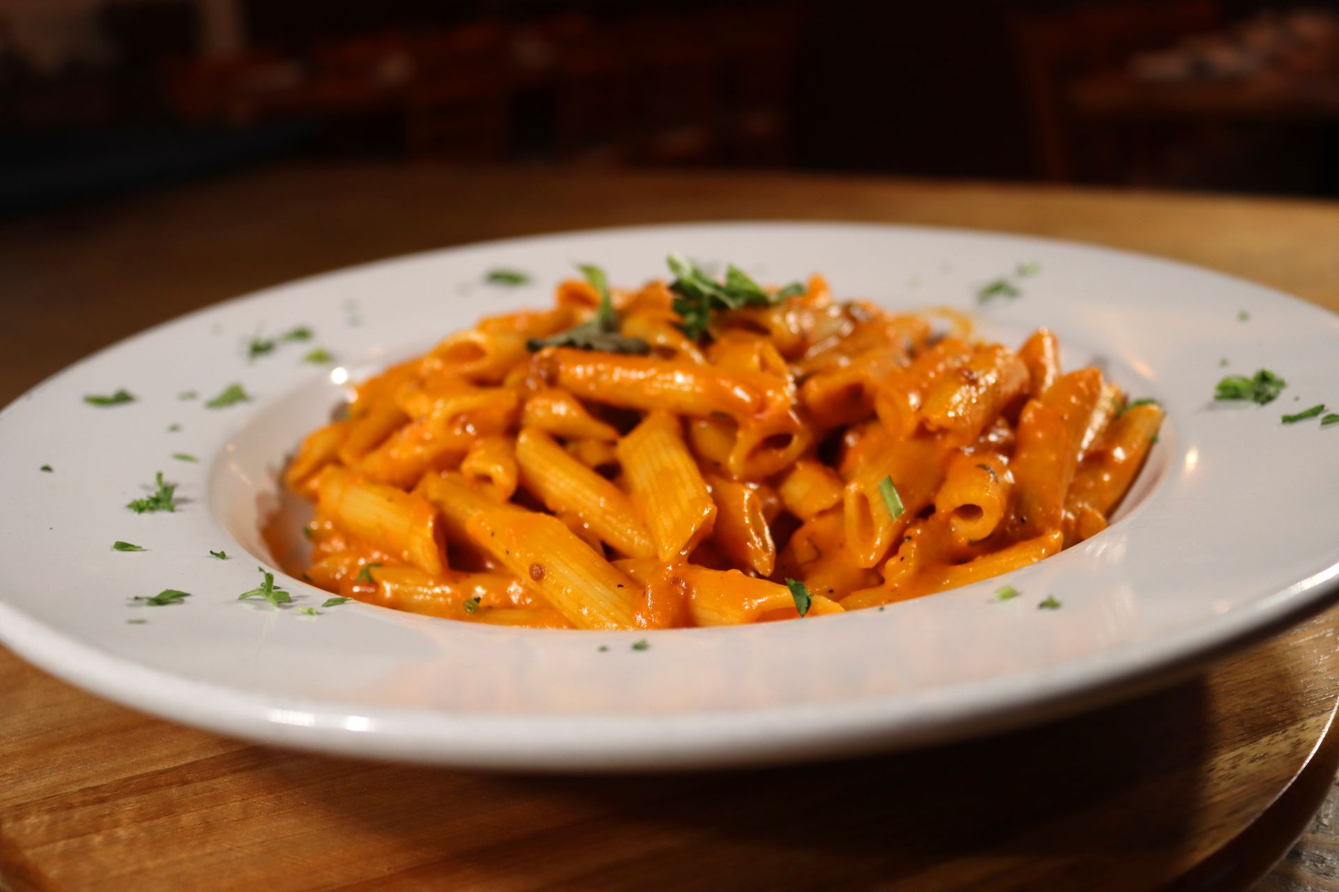 A white plate topped with pasta and sauce on a wooden table.