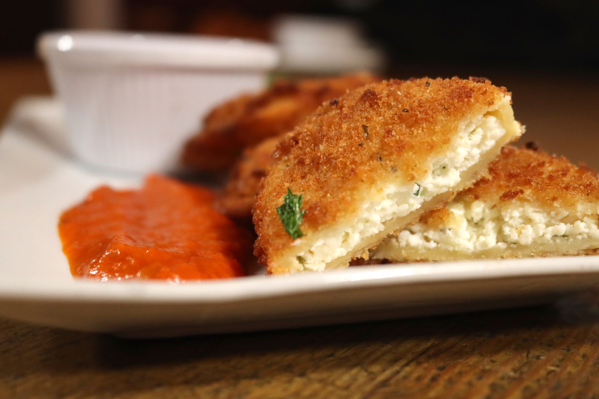 A white plate topped with fried food and sauce on a wooden table.