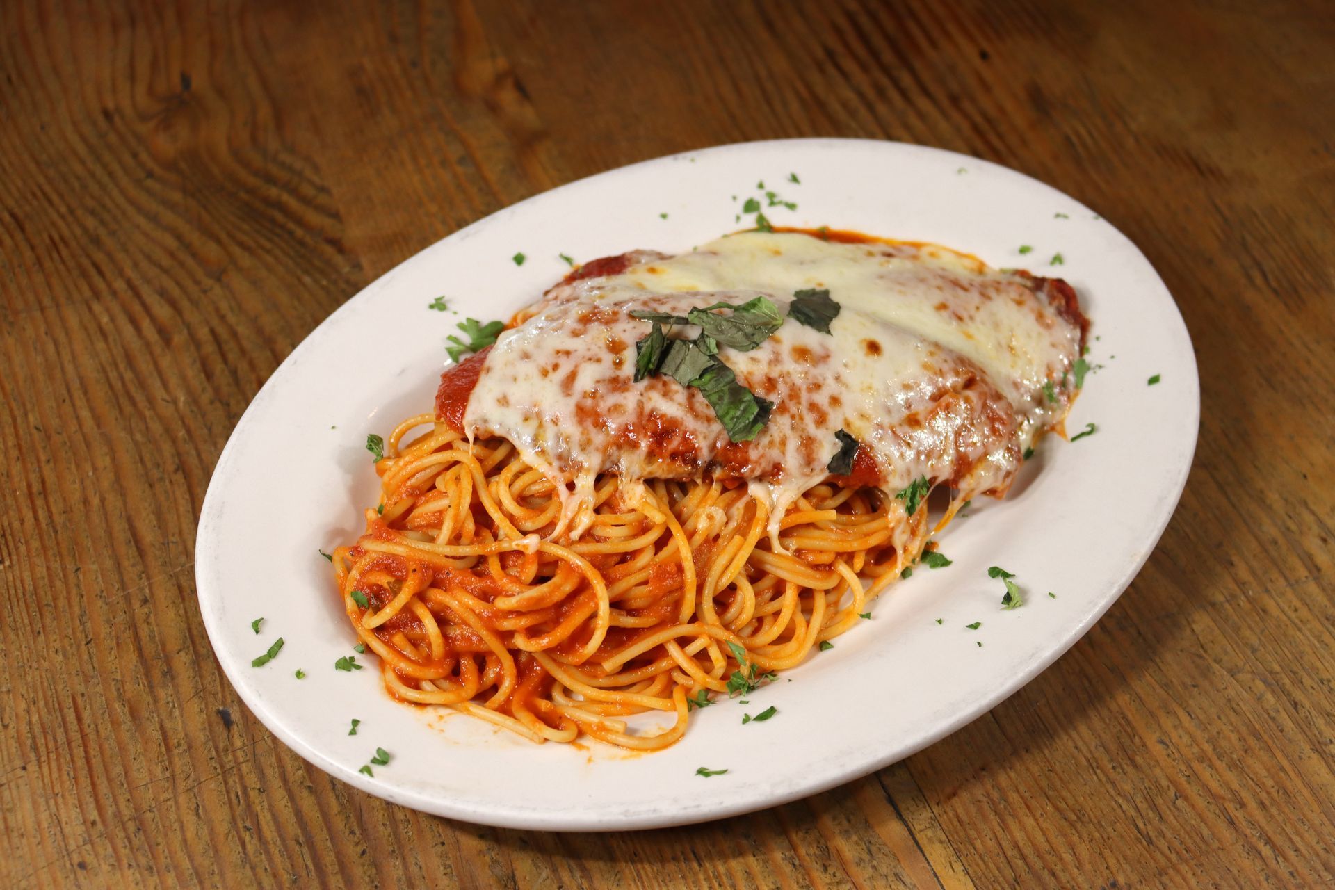 A white plate topped with spaghetti and meat on a wooden table.