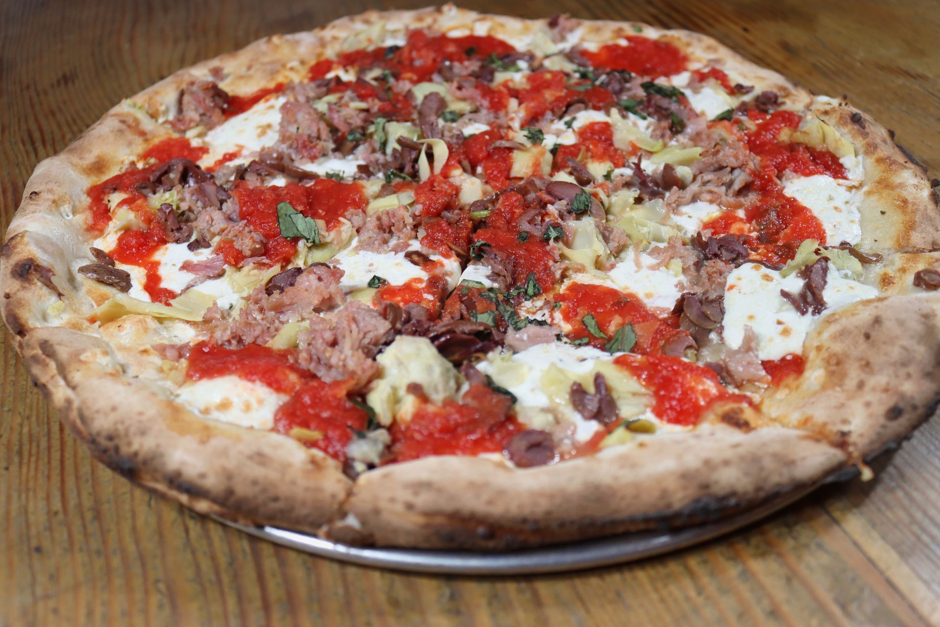 A pizza with a lot of toppings is sitting on a wooden table.