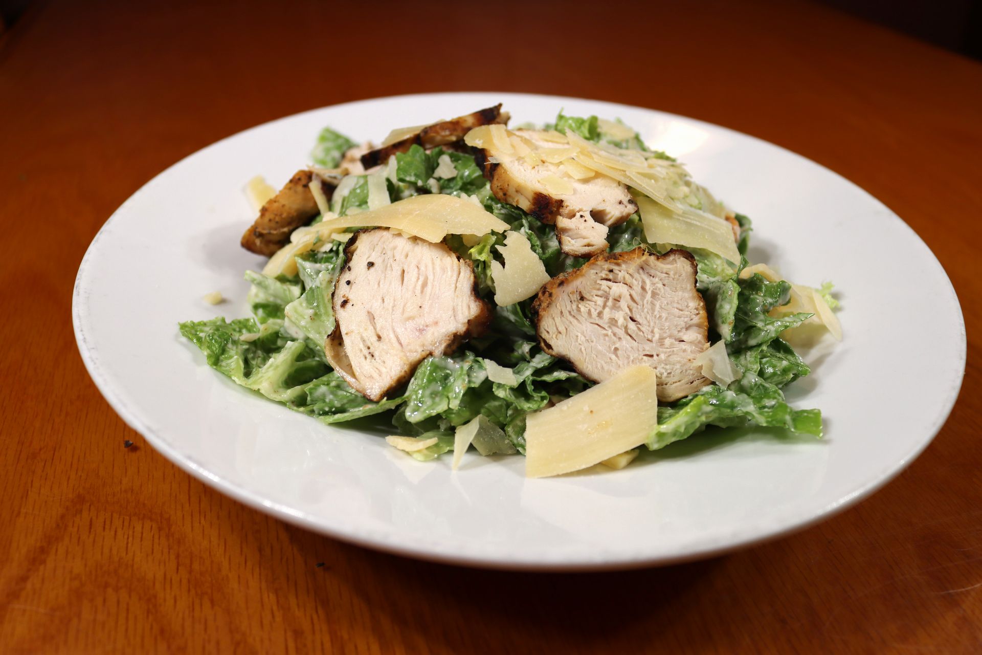 A white plate topped with a caesar salad on a wooden table.