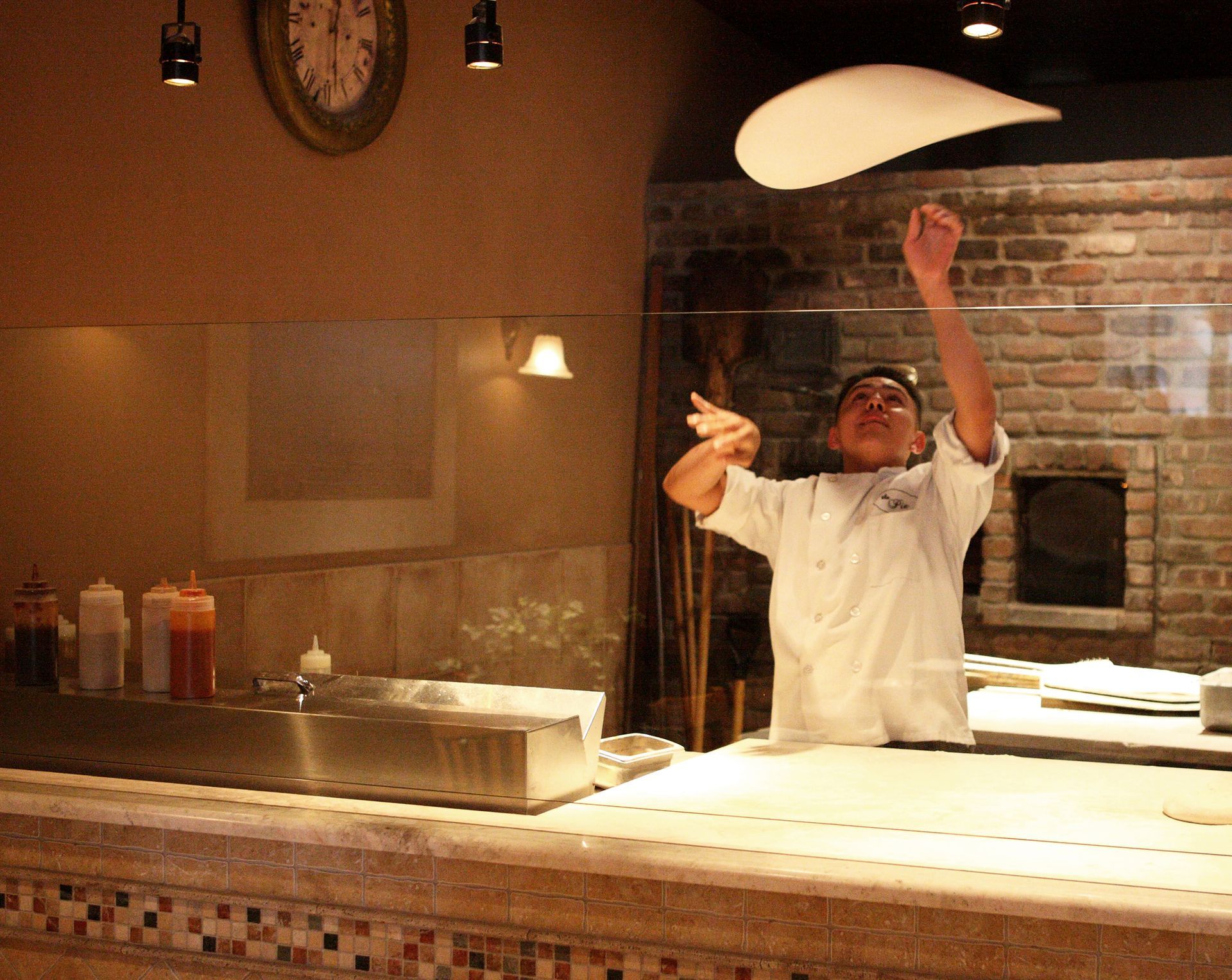 A man is throwing a pizza dough in the air