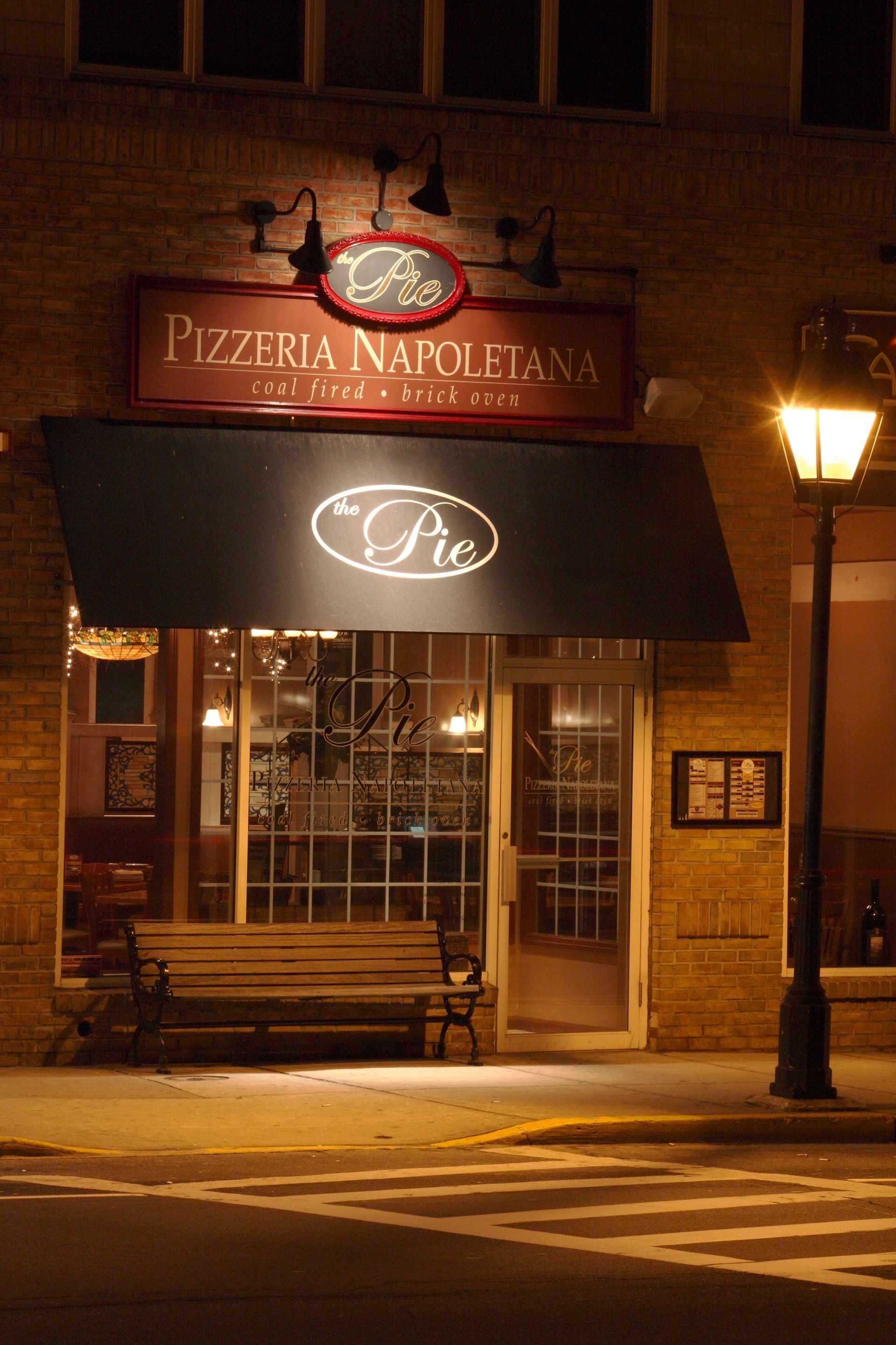 A restaurant called pizzeria napoletana is lit up at night