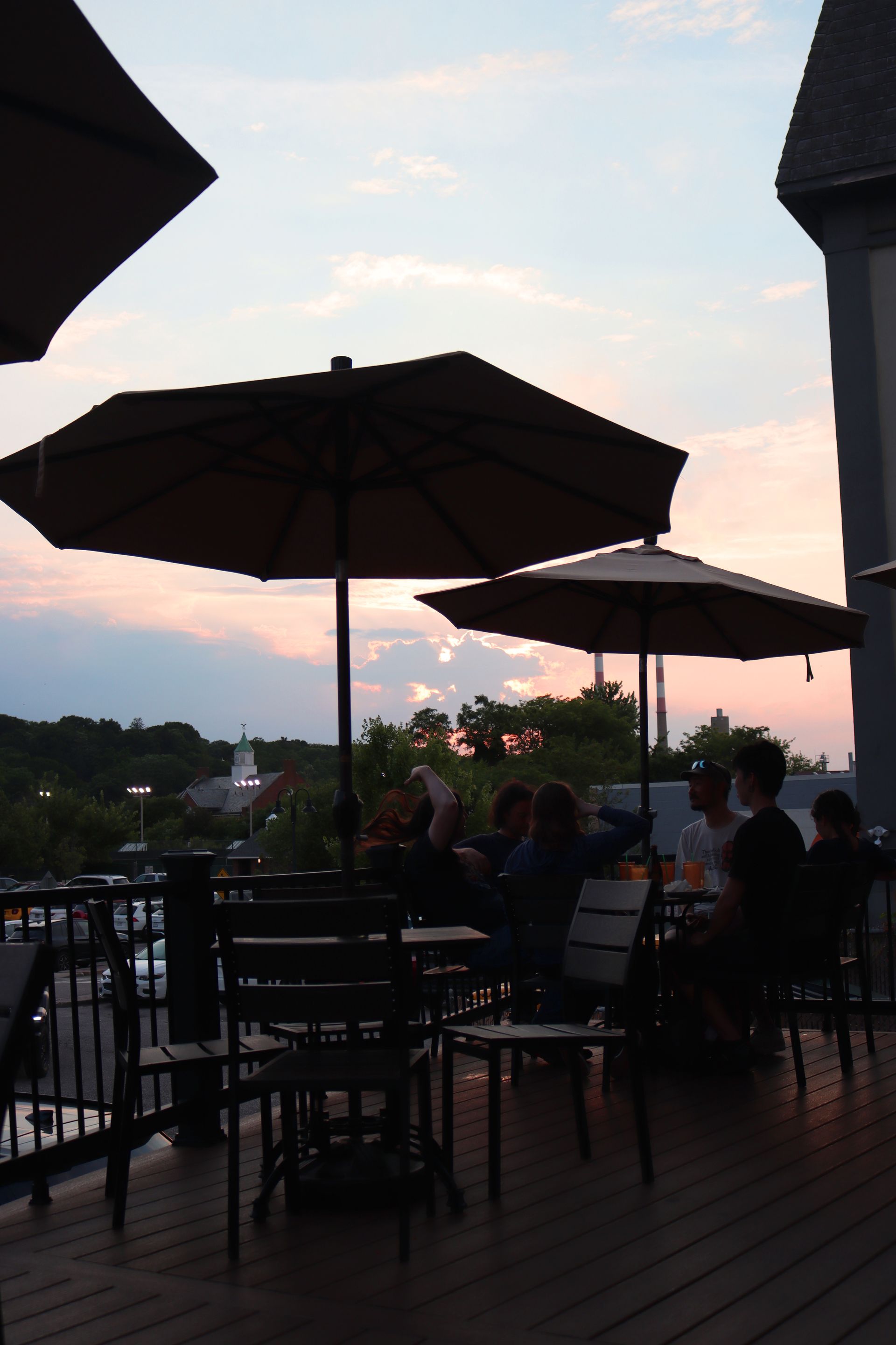 A group of people are sitting under umbrellas on a deck