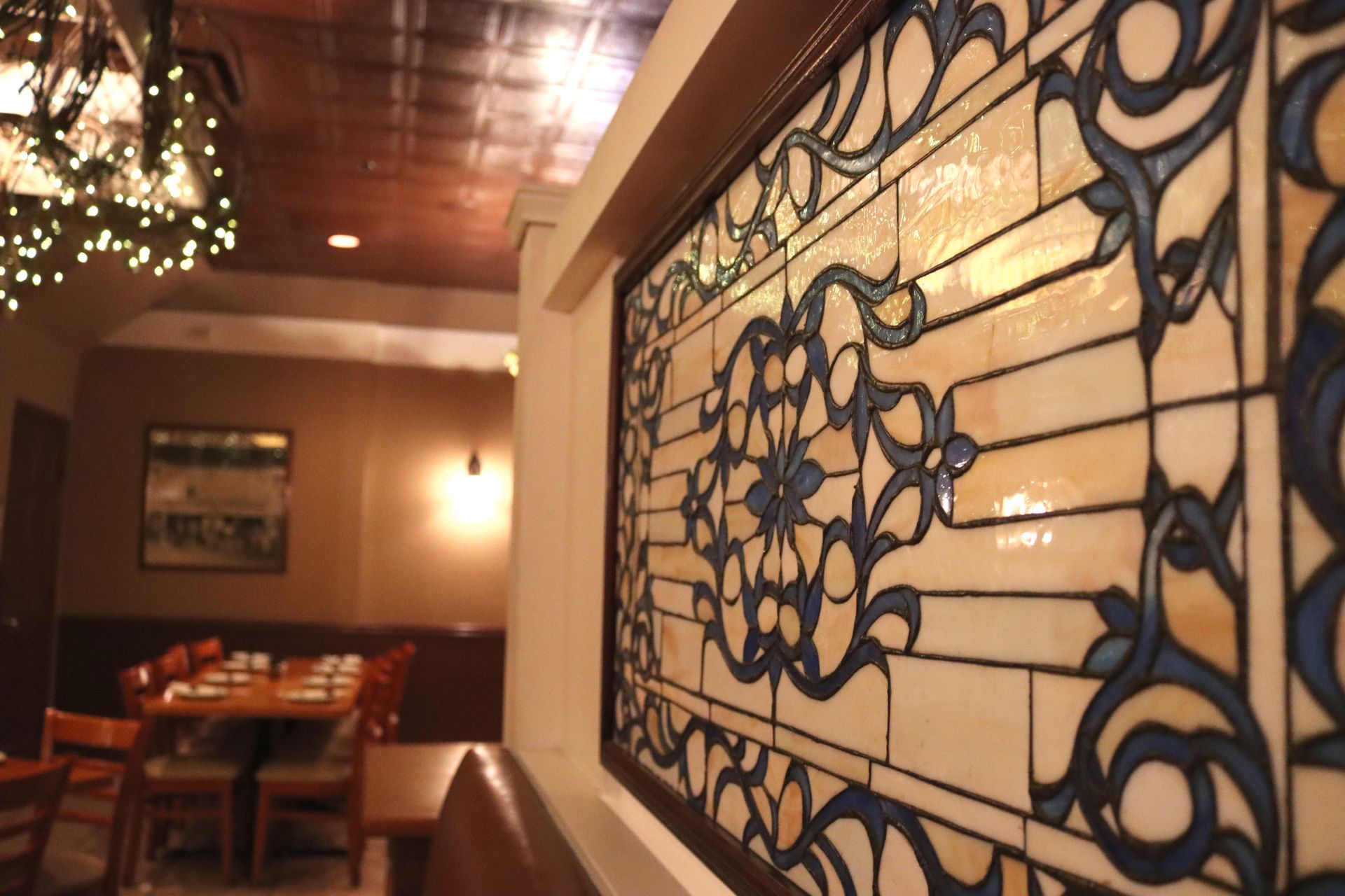 A stained glass window in a restaurant with tables and chairs in the background