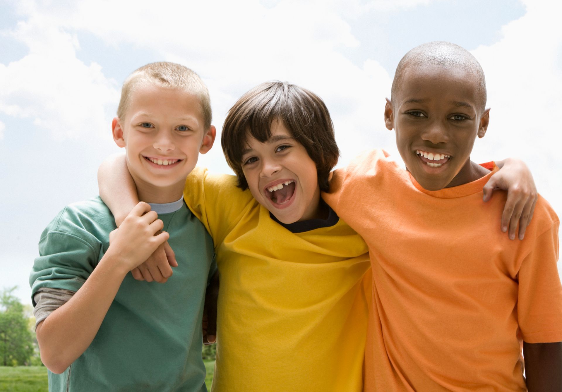 Two young boys are hugging each other and giving a thumbs up.