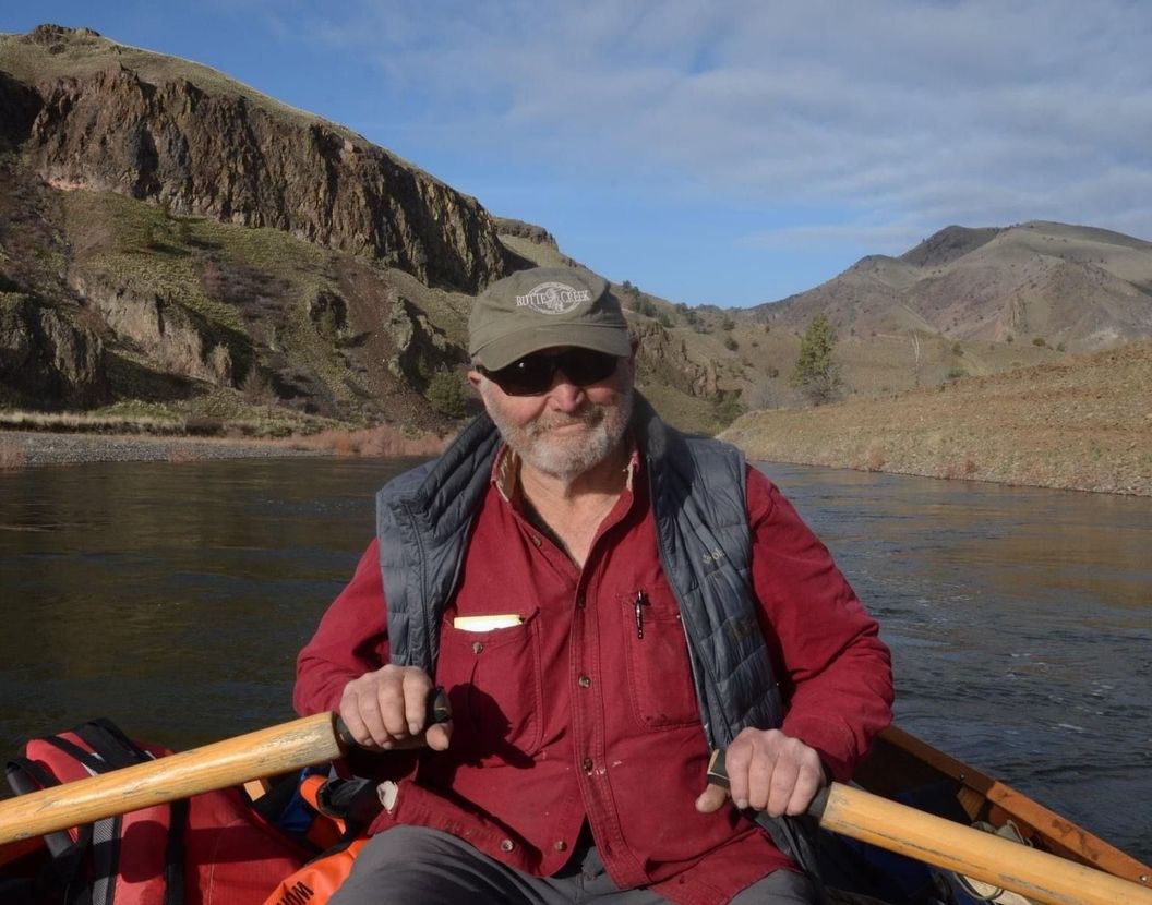 A man in a red shirt is rowing a boat on a river.