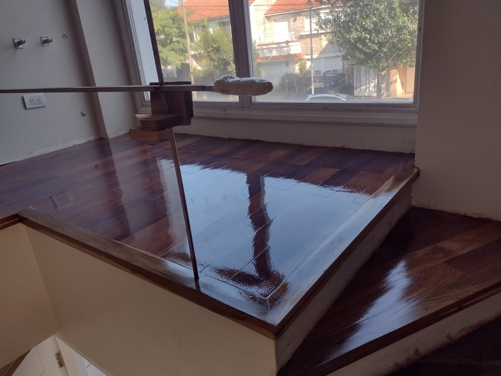 Una escalera de madera con barandilla de cristal y una ventana.